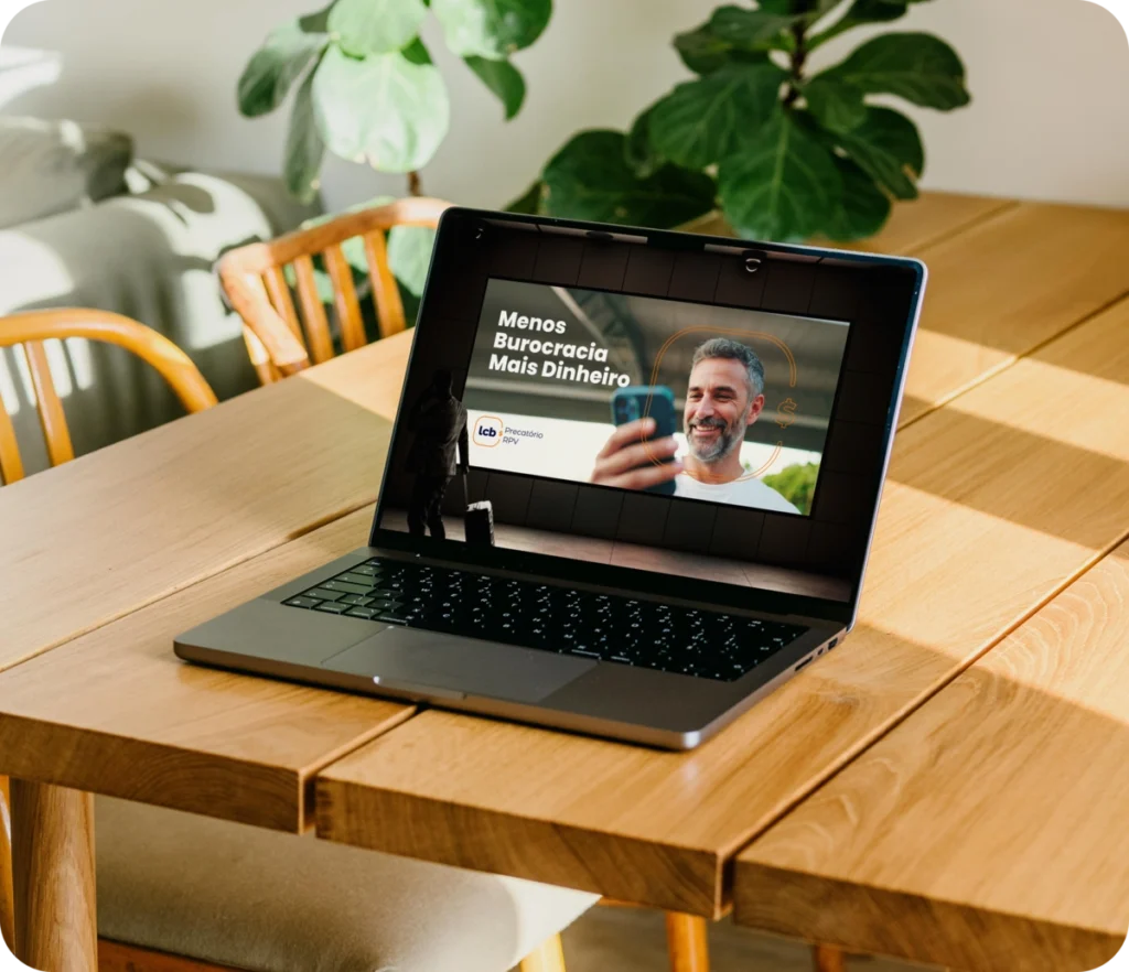 Laptop com mensagem "Menos Burocracia Mais Dinheiro" no monitor, em uma mesa